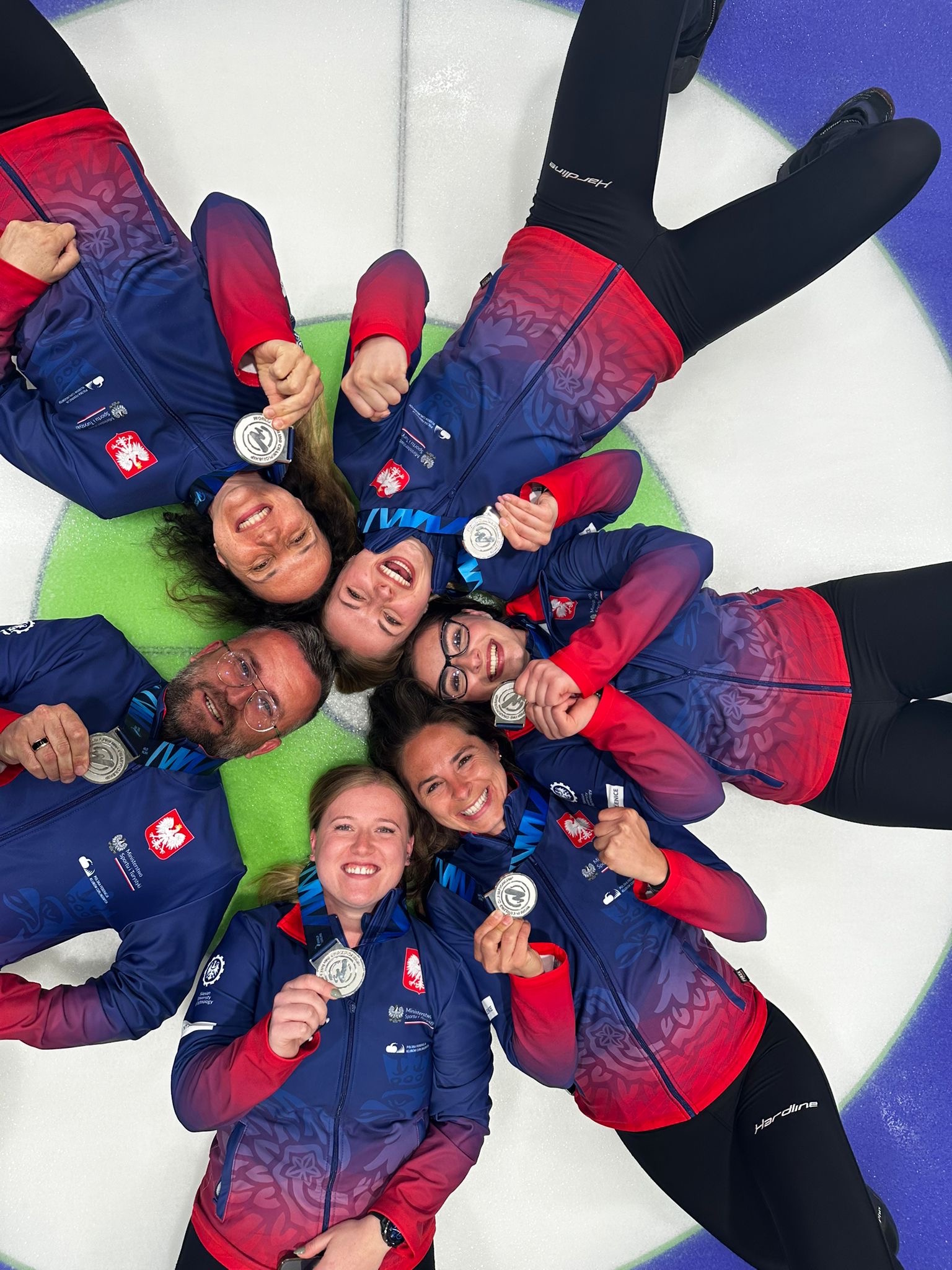 drużyna AZS Pluta Gliwice leżąca na lodowisku z medalami