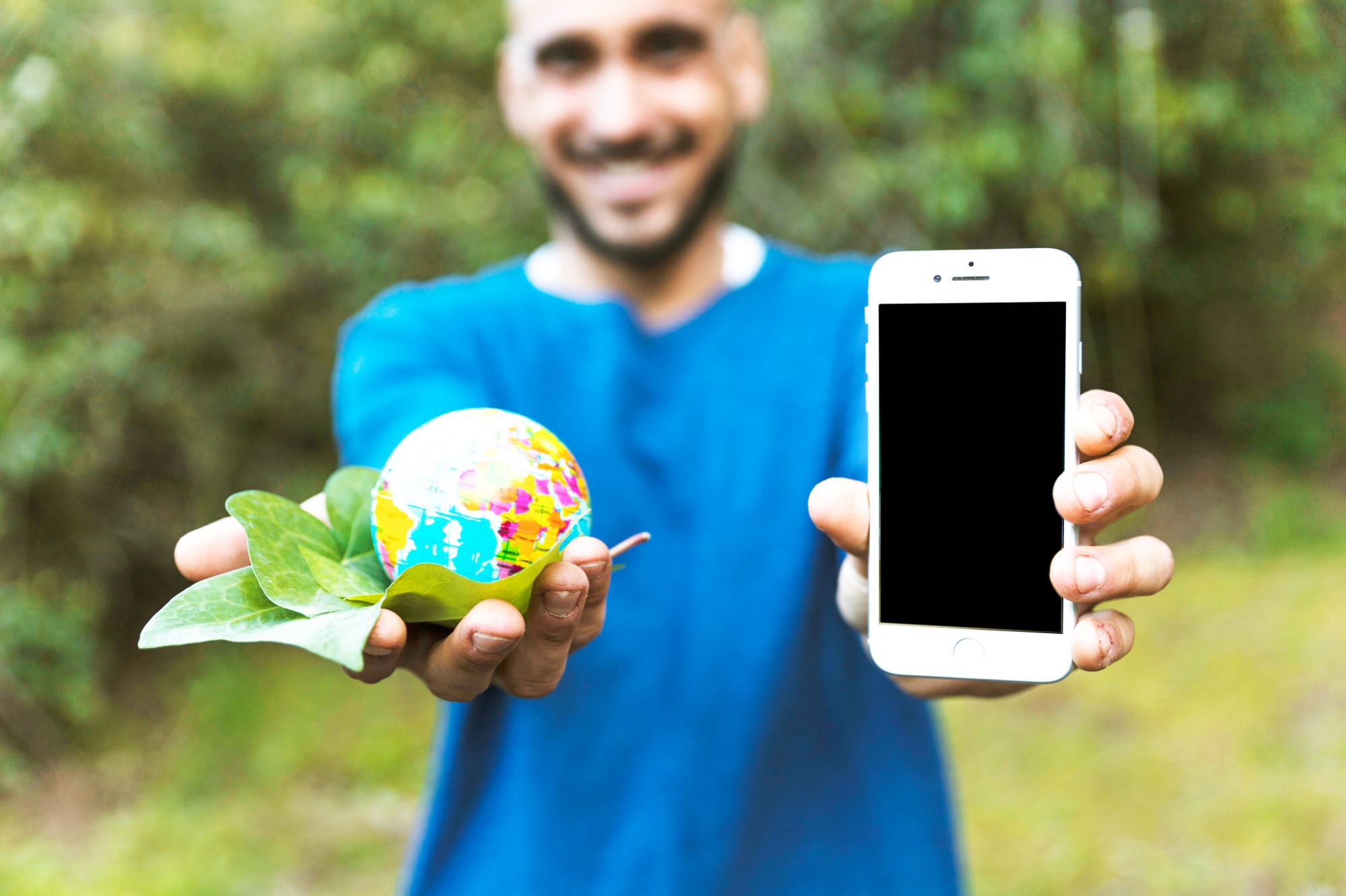 Mężczyzna trzymający w dłoniach smartfon i małą kulę ziemską